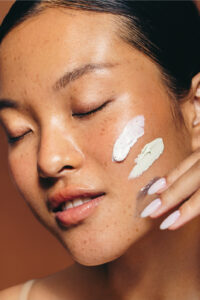 Woman applying moisturizer to her face as part of a daily skincare routine